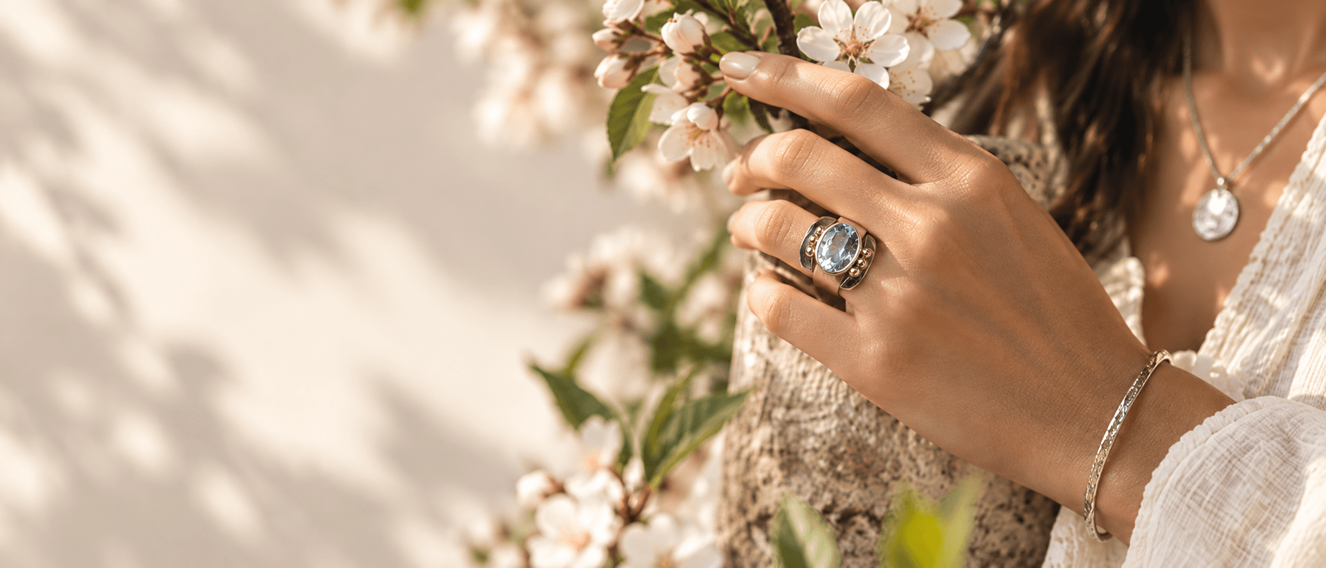 Mano con anillo de piedra azul entre flores para Primavera 2026
